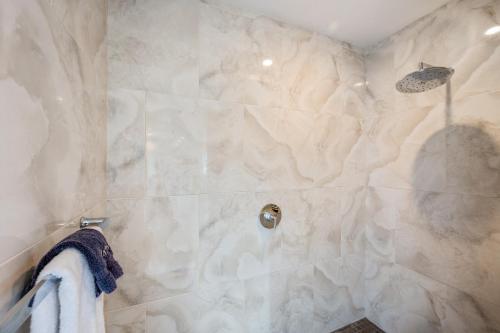 a bathroom with a shower with white marble walls at Lush, Airy Studio Loft Steps from the Walk of Fame in Los Angeles