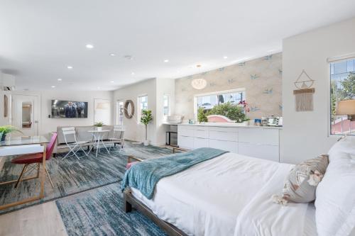 a white bedroom with a large bed and a kitchen at Lush, Airy Studio Loft Steps from the Walk of Fame in Los Angeles