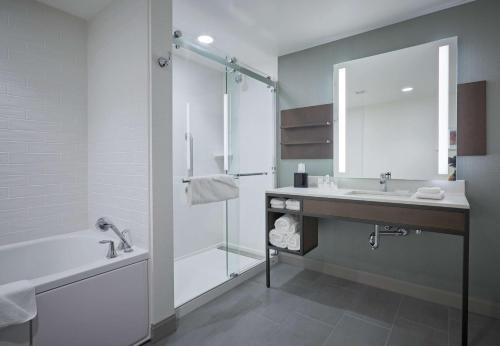 bagno con vasca, lavandino e specchio di Hilton Garden Inn Corning Downtown a Corning