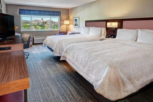 a hotel room with two beds and a flat screen tv at Hampton Inn Discovery Kingdom Napa Gateway in Vallejo