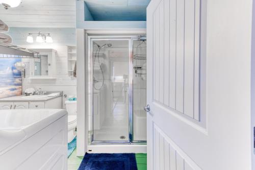 a white bathroom with a shower and a sink at Sand Dollar Cottage Rockaway - Meredith Lodging in Rockaway Beach