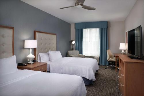 a hotel room with two beds and a flat screen tv at Homewood Suites By Hilton Cincinnati Midtown in Cincinnati