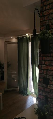 a room with a window with green curtains and a brick wall at Rustic in Vir