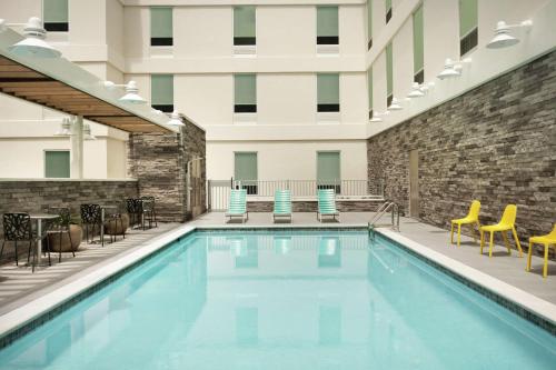 a pool in a hotel with chairs and a building at Home2 Suites By Hilton Sarasota Bradenton Airport in Sarasota