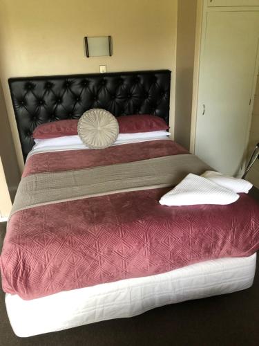 a bedroom with a large bed with a black headboard at Aarburg Airport Motel in Christchurch