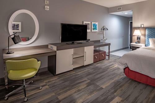 a bedroom with a bed and a desk with a television at Hampton Inn & Suites Dallas/Plano Central in Plano