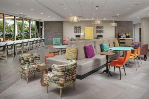a waiting room with a couch and tables and chairs at Home2 Suites By Hilton Lakeland in Lakeland