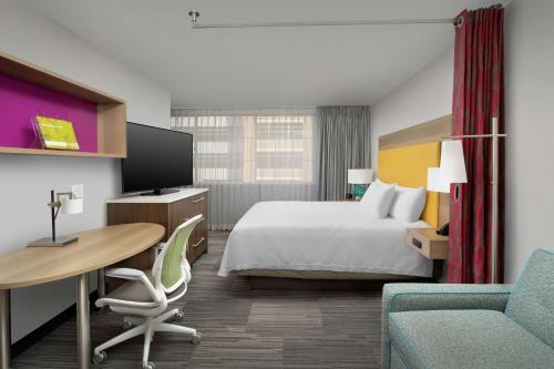 a hotel room with a bed and a desk and a table at Home2 Suites by Hilton Atlanta Midtown in Atlanta