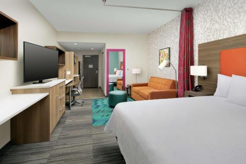 レイクランドにあるHome2 Suites By Hilton Lakelandのベッド1台、薄型テレビが備わるホテルルームです。