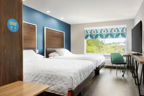 コロンビアにあるTru By Hilton Harbison Columbiaのベッド2台、デスク、窓が備わる客室です。