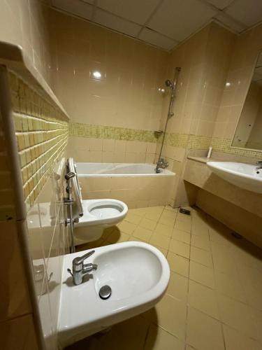 a bathroom with a sink and a toilet and a tub at MASTER BED G19 in Dubai