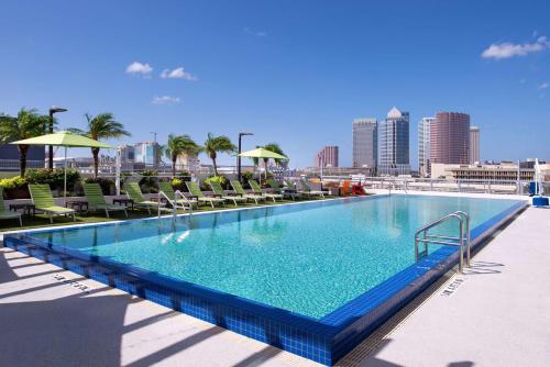 Hampton Inn Tampa Downtown Channel District في تامبا: مسبح كبير وكراسي وأفق المدينة