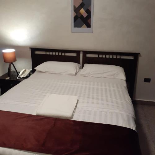 a bedroom with a large white bed with a phone at Tamrah Suites Hotel in Amman