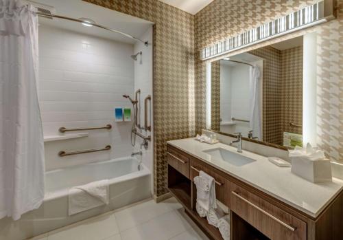 a bathroom with a tub and a sink and a mirror at Home2 Suites By Hilton Reno in Reno