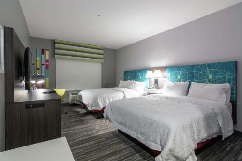 a hotel room with two beds and a television at Hampton Inn & Suites Dallas East in Dallas