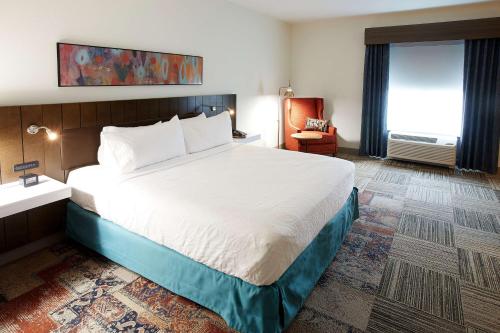 a hotel room with a large bed and a chair at Hilton Garden Inn Elizabethtown in Elizabethtown