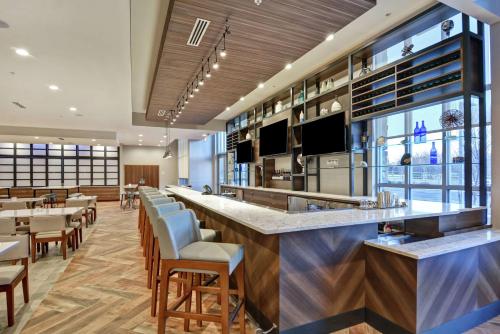 a restaurant with a bar with chairs and tables at Hilton Garden Inn Princeton Lawrenceville in Lawrenceville