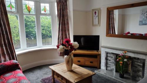 a living room with a vase of flowers on a table at Superior three bedroom house with sea view in Swansea