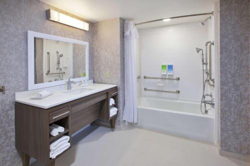 uma casa de banho com um lavatório, uma banheira e um chuveiro em Home2 Suites By Hilton Holland em Holland