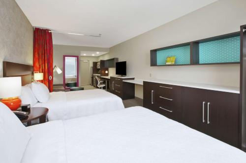 a hotel room with two beds and a tv at Home2 Suites By Hilton Holland in Holland