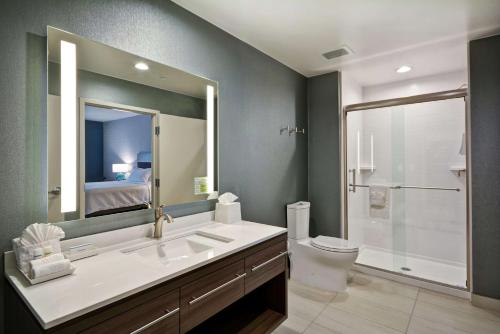 a bathroom with a sink and a toilet and a mirror at Home2 Suites Plano Legacy West in Plano