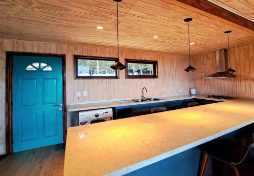 una cocina con una puerta azul y una barra en Lodge Tregualemu, en Cobquecura