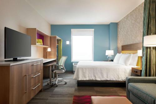 a hotel room with a bed and a flat screen tv at Home2 Suites By Hilton Brooklyn Park Minneapolis in Brooklyn Park