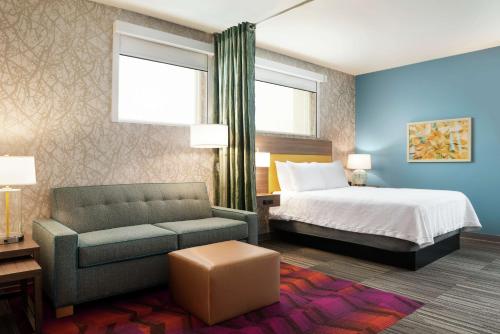 a hotel room with a bed and a couch at Home2 Suites By Hilton Brooklyn Park Minneapolis in Brooklyn Park