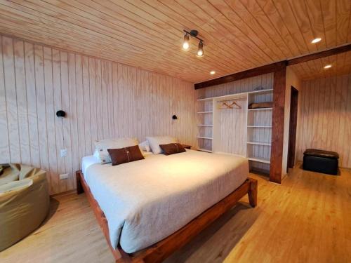 1 dormitorio con 1 cama grande en una habitación de madera en Lodge Tregualemu, en Cobquecura