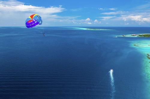 a person flying a kite over a body of water at SAii Lagoon Maldives, Curio Collection By Hilton in South Male Atoll