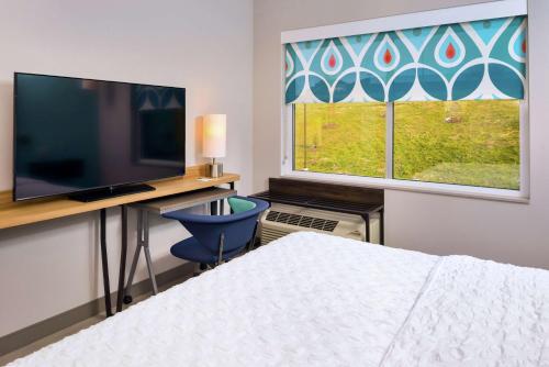 a bedroom with a bed and a desk with a television at Tru By Hilton Staunton in Staunton