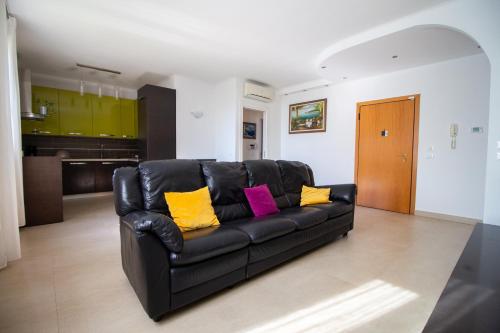 a black leather couch with yellow and pink pillows in a living room at La Dolse Ca' - Lago di Garda in Brenzone sul Garda