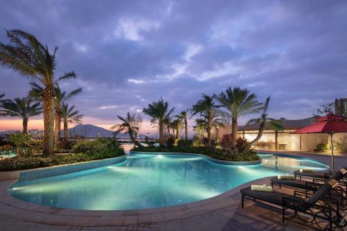 - une piscine avec des palmiers dans un complexe dans l'établissement Doubletree By Hilton Huidong Resort, à Huidong