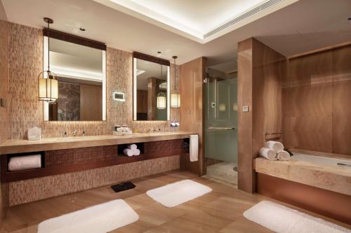 a bathroom with two sinks and a tub and mirrors at Doubletree By Hilton Huidong Resort in Huidong