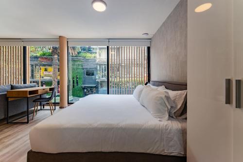 a bedroom with a bed and a table and a desk at Condesa Cholula Lofts by VH in Mexico City