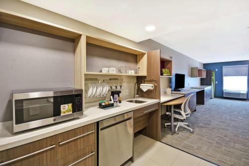 a kitchen with a counter with a microwave and a desk at Home2 Suites By Hilton Warner Robins in Warner Robins