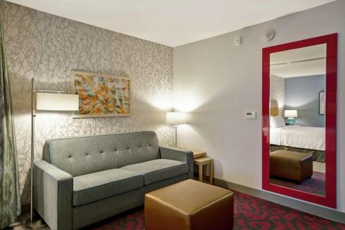 a hotel room with a couch and a mirror at Home2 Suites By Hilton Warner Robins in Warner Robins