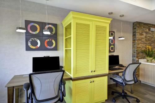 a yellow cabinet in a room with a desk and chairs at Home2 Suites By Hilton Warner Robins in Warner Robins