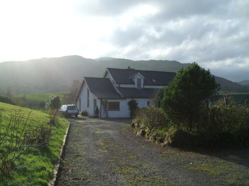 a white house with a car parked on a dirt road at Kenmare Eco Lodge in Kenmare