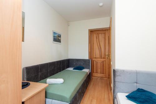 a small room with a green bed and a door at Palanga 777 - poilsio namai prie Birutės parko ir jūros in Palanga