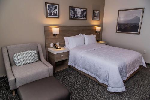 a hotel room with a bed and a chair at Hampton Inn & Suites By Hilton Puebla in Puebla