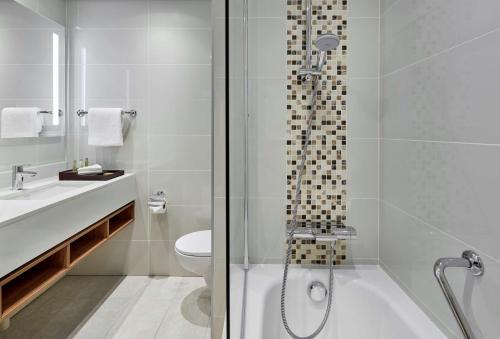 a bathroom with a shower and a toilet and a sink at Hilton Garden Inn Gaborone, Botswana in Gaborone