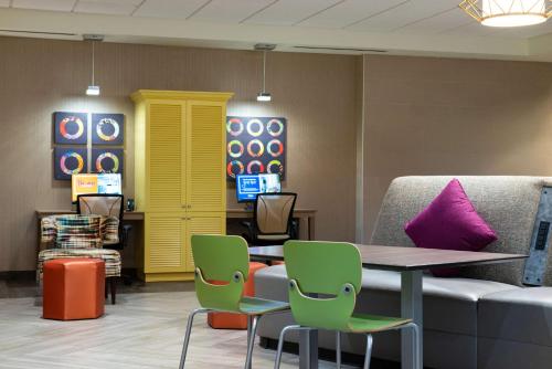a waiting room with a couch and a table and chairs at Home2 Suites By Hilton Charlotte Mooresville, Nc in Mooresville