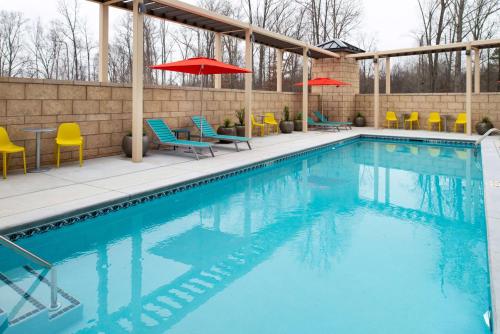 a swimming pool with chairs and umbrellas on a building at Home2 Suites By Hilton Charlotte Mooresville, Nc in Mooresville