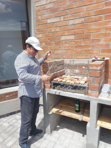a man is standing next to a grill at El Chasqui Guest House in Chasqui