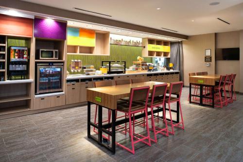 a restaurant with a bar with red chairs and tables at Home2 Suites By Hilton Charlotte Mooresville, Nc in Mooresville