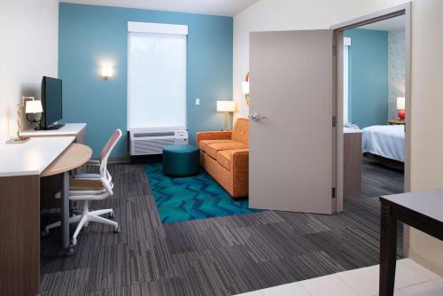a hotel room with a desk and a room with a bed at Home2 Suites By Hilton Charlotte Mooresville, Nc in Mooresville