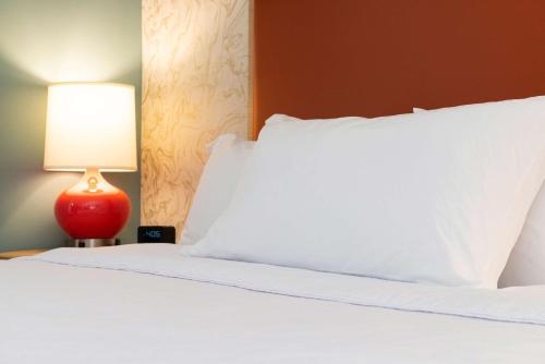 a bed with a white pillow and a red lamp at Home2 Suites By Hilton Charlotte Mooresville, Nc in Mooresville