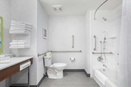 La salle de bains blanche est pourvue d'une douche et de toilettes. dans l'établissement Hampton Inn Simpsonville, à Simpsonville