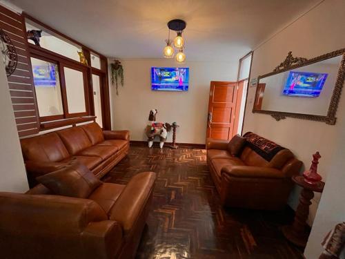 sala de estar con sofás de cuero y TV en Casa hospedaje Ingeniería - Lima en Lima